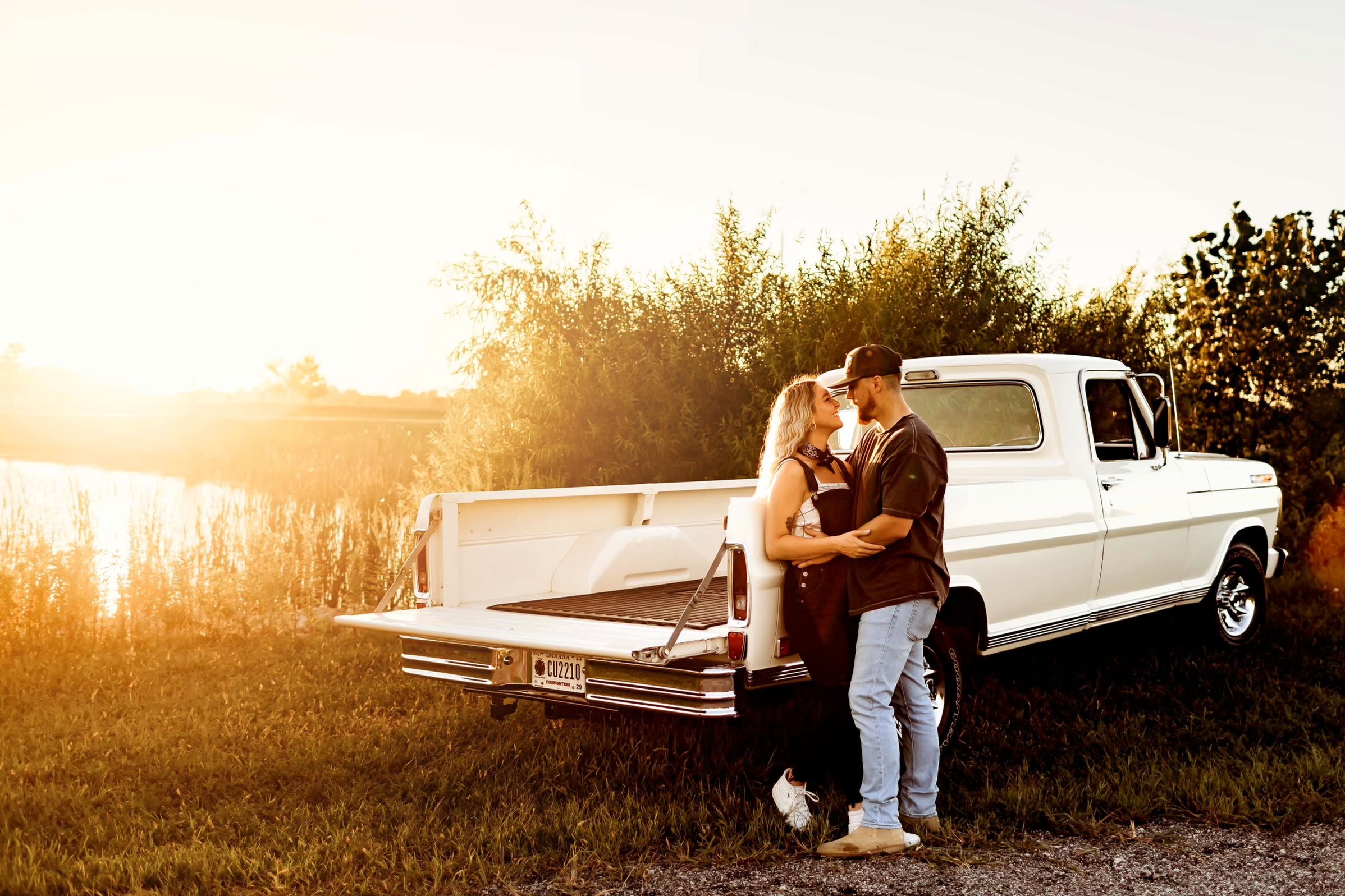 Liz and her husband beside a white vintage pickup at golden hour